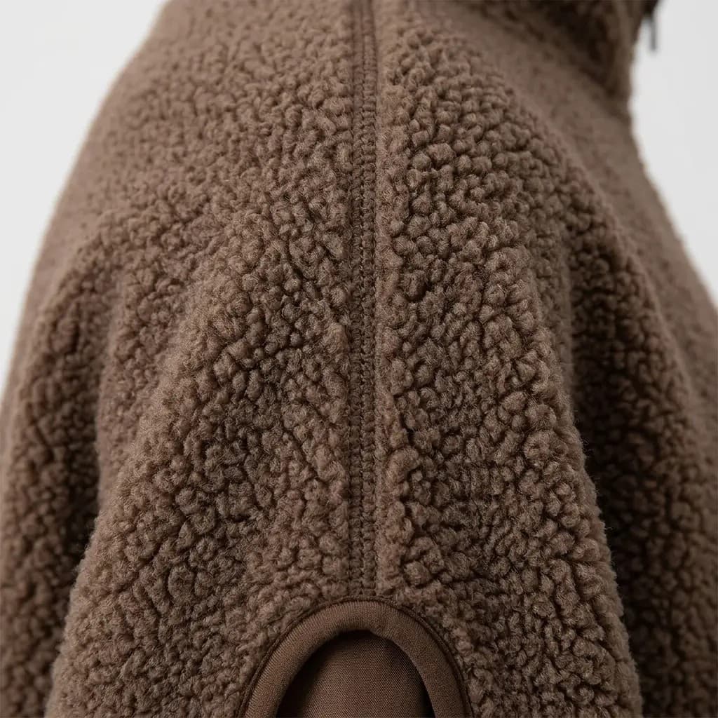 Close-up of the sherpa fleece texture and stitched pocket on this oversized half-zip pullover.